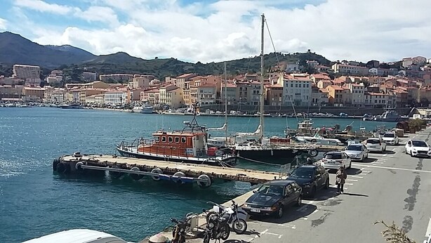 A marina with boats docked, a docked tugboat, and a row of parked cars along the waterfront. - DUPLEX OF 110 M2 NEAR QUAY AND SHOPS, 8 persons (Port-Vendres)