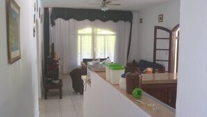 A spacious living area with a kitchen counter, a dining table, and a ceiling fan. - Six lakes site in the Juquitiba region (Dos Barnabés)