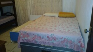 A small, single-bed room with a floral bedspread, a wooden headboard, and a door with a silver handle. - Six lakes site in the Juquitiba region (Dos Barnabés)