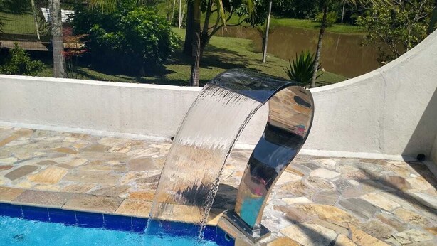 A swimming pool with a stone-tiled deck and a waterfall feature. - Six lakes site in the Juquitiba region (Dos Barnabés)