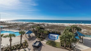 Un resort frente a la playa con piscina, sillas de descanso y una pequeña zona de juegos.