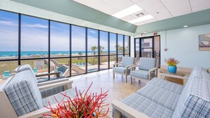 Una habitación amplia con ventanas grandes, vista a la piscina y un área de descanso con una planta.
