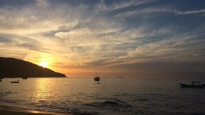 A sunset over a calm sea with boats and a distant landmass. - Camping do Bené (Angra dos Reis)
