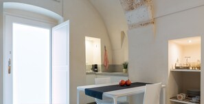 Une cuisine moderne avec des meubles blancs, un plan de travail et un porte-ustensiles suspendu.