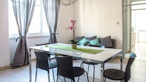 A modern dining area with a white table, black chairs, a green placemat, and a potted orchid.