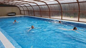 Ein Hallenbad mit großen Glaswänden, einem Sprungbrett und einer Sitzbank.