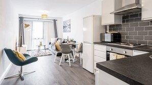 Une cuisine moderne avec un coin repas, comprenant un four à micro-ondes encastré, une cuisinière et des meubles de cuisine blancs.