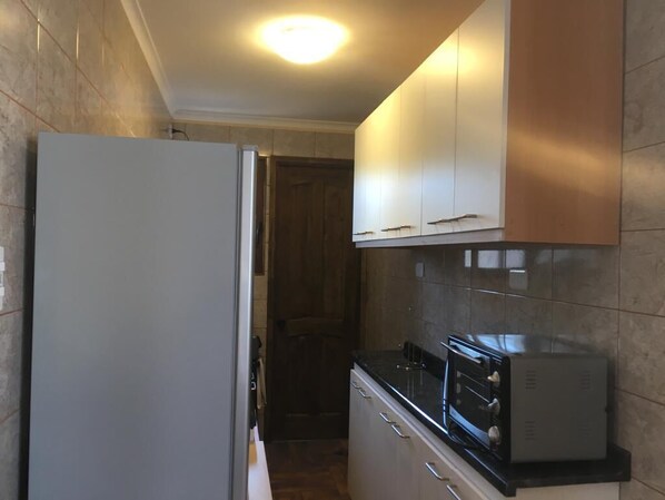 A compact kitchen with a refrigerator, oven, and cabinets.