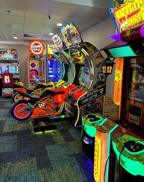 A row of arcade games including a motorcycle racing game, a Super Wheel, and a Wild Shoot game.