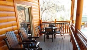 Een houten chalet met een veranda, voorzien van schommelstoelen en een tafel.