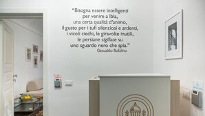 Un vestíbulo de hotel con una cita en la pared, un mostrador de recepción y una puerta que da a una habitación.