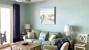 A living room with a ceiling fan, a sofa, a coffee table, a chair, and a painting on the wall. -  Fantastic Gulfview condo 1 br/2 ba , bunk , sleep 6 (Panama City Beach)
