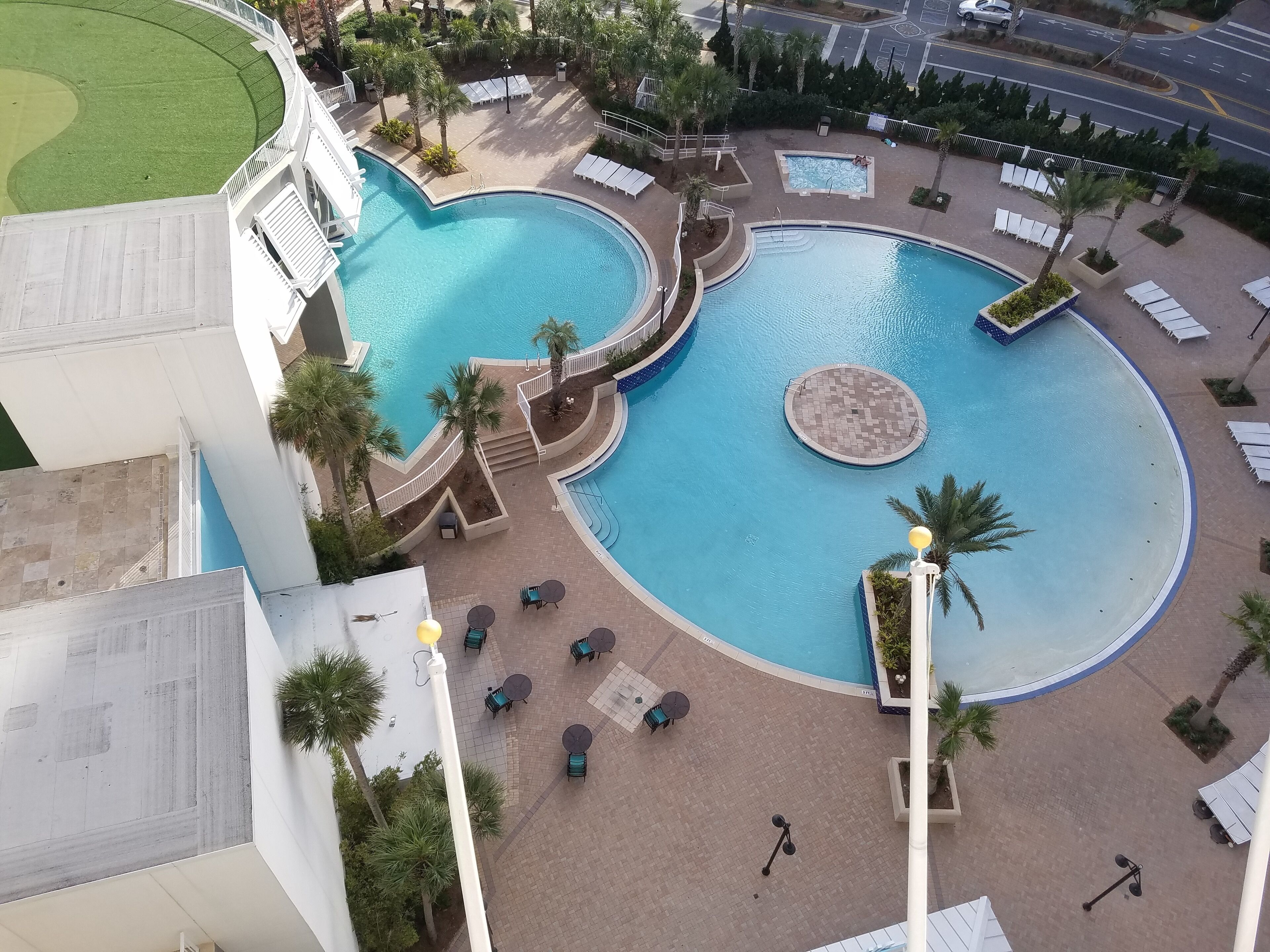 Una gran piscina al aire libre con varias secciones y zonas de descanso alrededor.