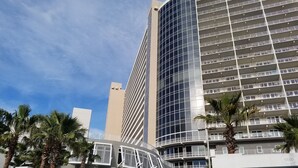 A modern hotel with a curved facade, multiple balconies, and palm trees in the foreground. -  Fantastic Gulfview condo 1 br/2 ba , bunk , sleep 6 (Panama City Beach)