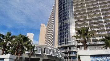 Un hotel moderno con fachada curva, varios balcones y palmeras en primer plano.