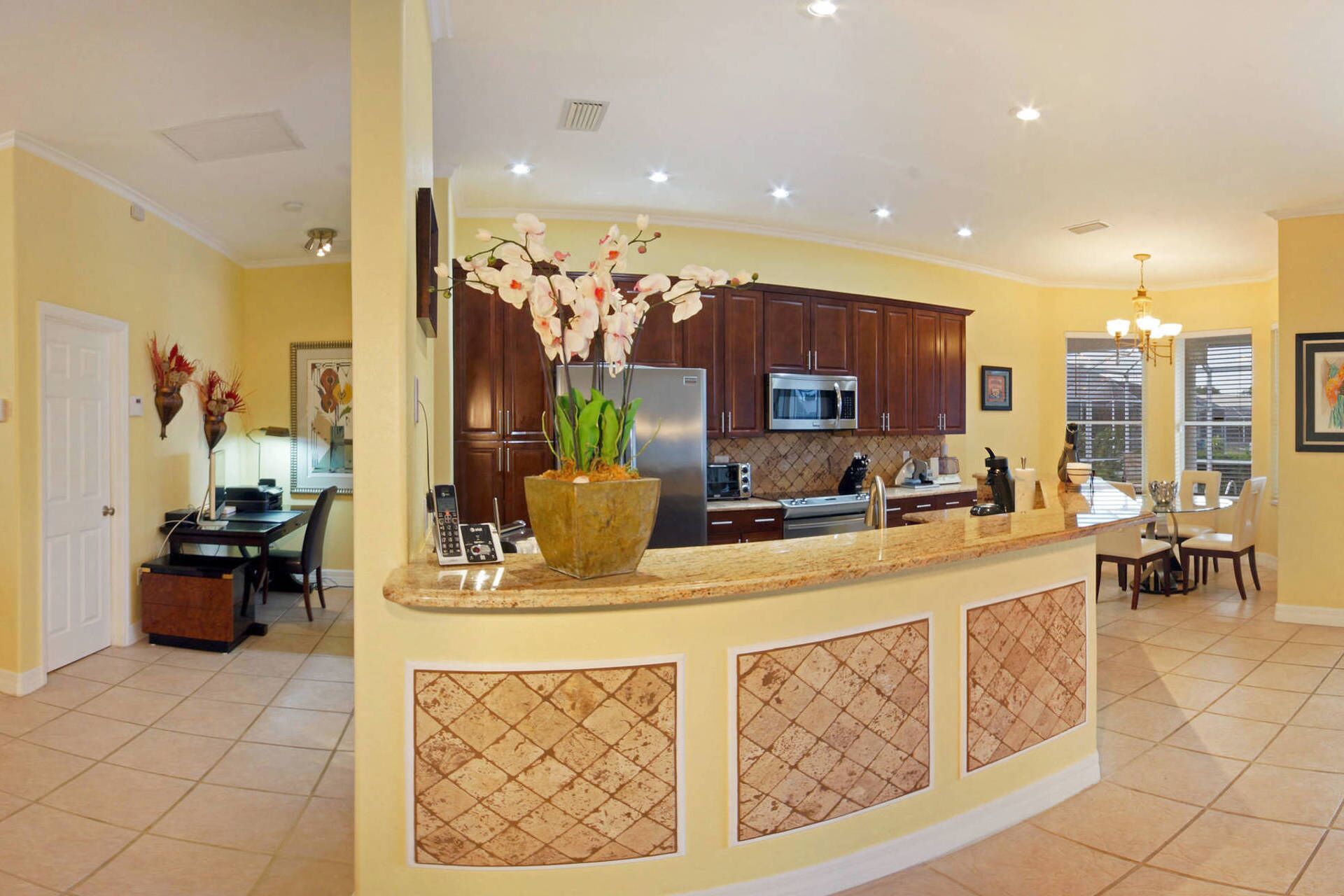 A modern kitchen with a curved island, stainless steel appliances, and a dining area with a table and chairs.
