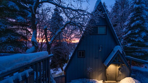 A cabin with a steeply pitched roof, a small porch, and a door leading to the entrance. - Stylish A-Frame (Eden)