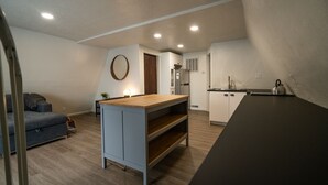 A compact kitchen with a wooden island, a built-in fridge, and a sink. - Stylish A-Frame (Eden)