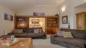 Ein gemütliches Wohnzimmer mit zwei Sofas, einem Couchtisch und einer Bücherwand voller Bücher und Dekoration.