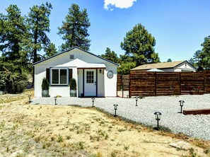 A small, single-story building with a white exterior, a front door, and a small porch area.