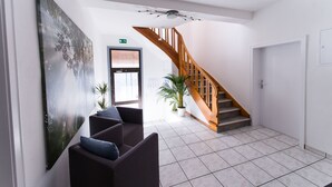 A modern lobby with a wooden staircase, a large abstract painting, and two seating areas. - P1 - Large apartment at the gates of Kassel (Fuldatal)
