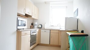 A kitchen with light wooden cabinets, a microwave, an oven, a dishwasher, and a coffee maker. - P4 - Large apartment at the gates of Kassel (Simmershausen)