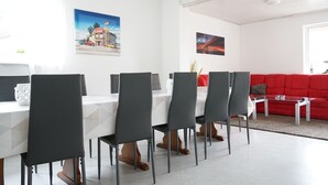 A modern dining area with a white table and black chairs, a red sofa, and two wall art pieces. - P4 - Large apartment at the gates of Kassel (Simmershausen)