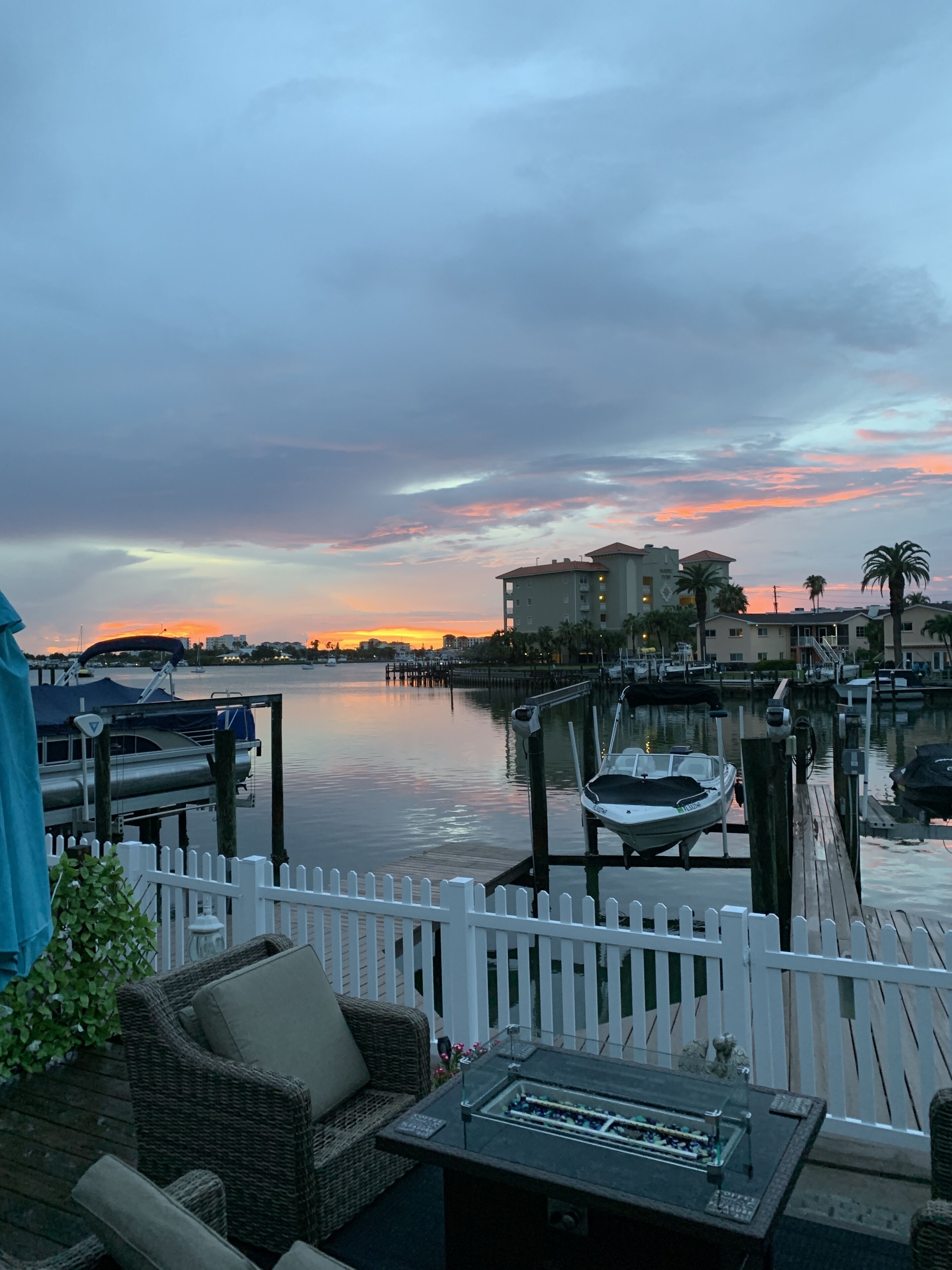 A waterfront patio with a white picket fence, a wicker sofa, and a foosball table.