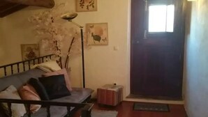 A cozy living room with a wooden floor, a sofa with cushions, a floor lamp, and artwork on the walls. - True "Village Refuge" in Monsaraz (pets allowed!)  (Monsaraz)