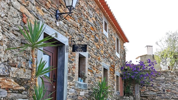 A stone building with a wooden door, a signboard, and a potted plant. - True "Village Refuge" in Monsaraz (pets allowed!)  (Monsaraz)