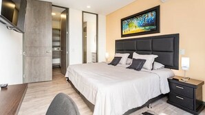 Une chambre d’hôtel moderne avec un grand lit, une télévision, un tableau au mur et une armoire.