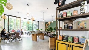 Un café moderne avec des meubles en bois, de grandes fenêtres et une variété de produits emballés exposés sur des étagères.