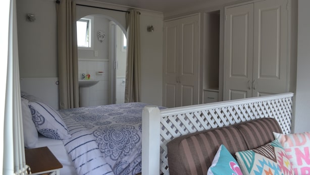 A bedroom with a bed, a nightstand, a dresser, and a wardrobe. - The Lighthouse (Torbay)