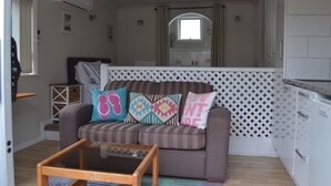 A compact living space with a sofa, a coffee table, and a kitchen area. - The Lighthouse (Torbay)
