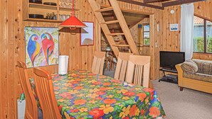 Un intérieur en bois comprenant une table à manger, des chaises, un canapé, un téléviseur et un tableau.