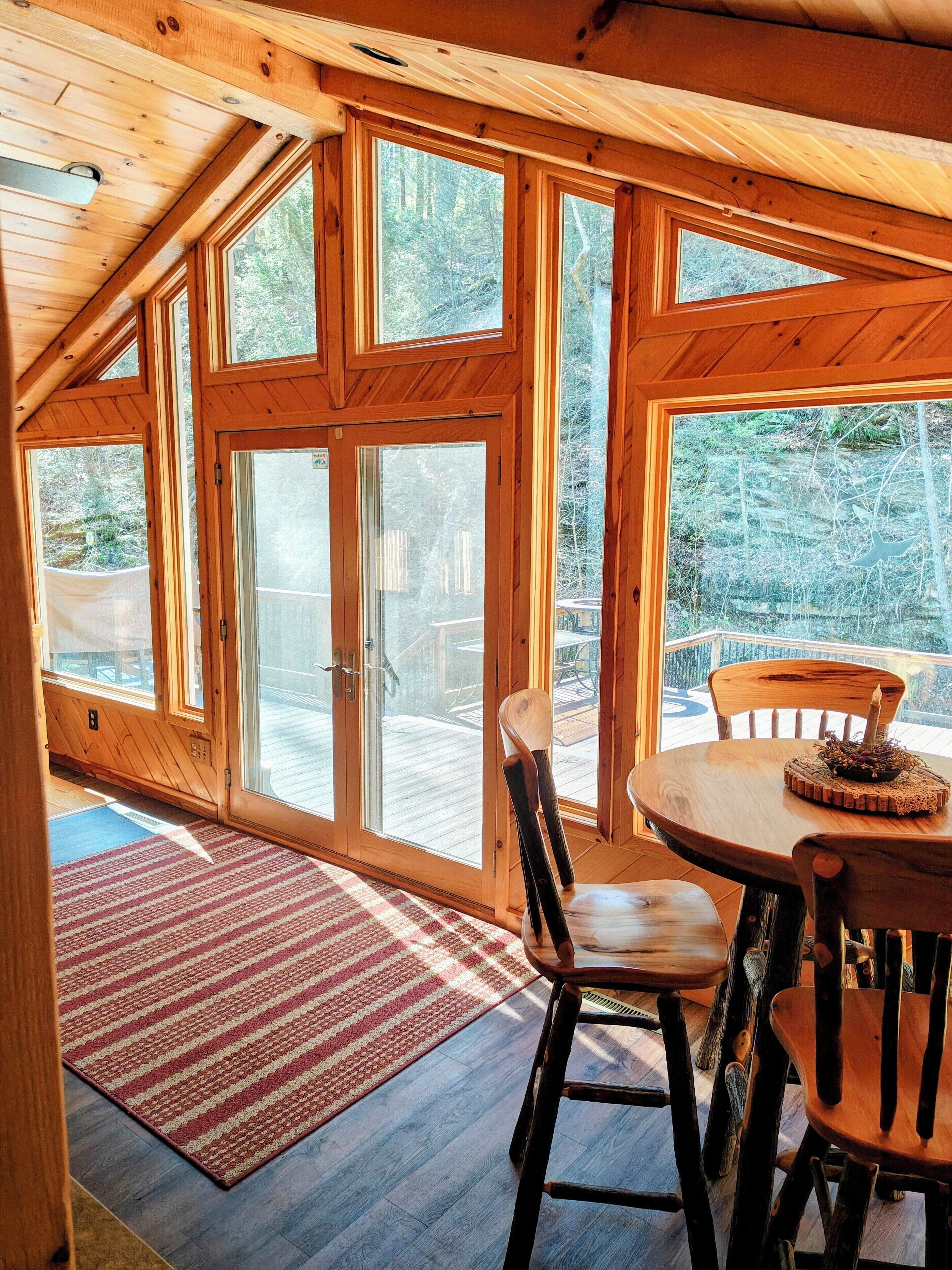 Dining. Beautiful 2 BR cabin with a wall of windows overlooking the deck and stream.