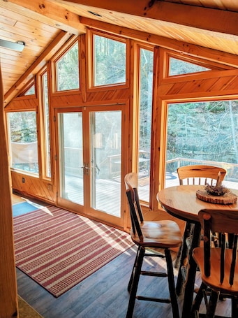Dining. Beautiful 2 BR cabin with a wall of windows overlooking the deck and stream.