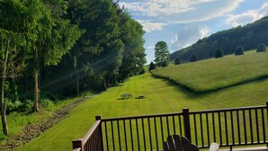 A deck with a view of a grassy field and trees. - Romantic hideaway on the lake nestled in the pines 79 miles north of Pittsburgh. (Ringgold)