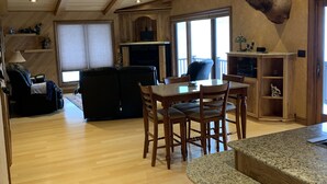 A spacious living area with a high ceiling, wooden beams, a fireplace, and a mounted deer head. - Romantic hideaway on the lake nestled in the pines 79 miles north of Pittsburgh. (Ringgold)