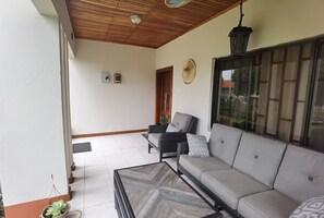 Un balcon spacieux avec un plafond en bois, un canapé, une table basse et une plante en pot.