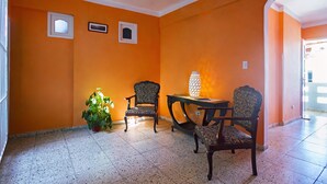 Ein Zimmer mit orangefarbenen Wänden, zwei Stühlen, einem Tisch und einer Topfpflanze.