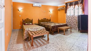 Ein Zimmer mit zwei Betten, einer hölzernen Bank, einem Ventilator und einer Klimaanlage.