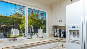 A modern kitchen with a large window, a sink, a coffee maker, and a water dispenser.