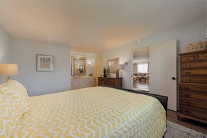 Ein Schlafzimmer mit einem großen Bett, einem Schminktisch, einem Spiegel und einem Nachttisch.