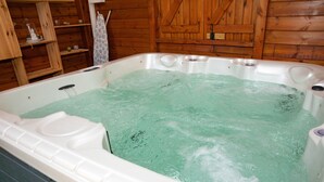 Un bain à remous dans un chalet en bois, avec des étagères et un porte-serviettes.