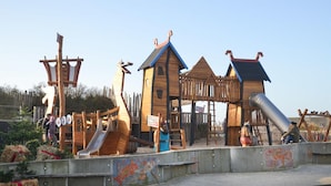 A wooden play structure with slides and climbing areas.