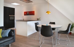 Enjoy meals at the round dining table with four chairs, or relax on the black leather sofa with colorful cushions.
