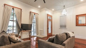 A living room with two sofas, a TV, and a chandelier. - Historic Mini-Mansion on Canal St. Walk to (New Orleans)