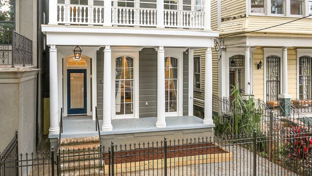 A two-story house with a balcony, a front door, and a small front yard with a fence. - Historic Mini-Mansion on Canal St. Walk to (New Orleans)