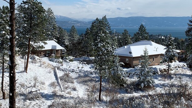 A snow-covered landscape with two cabins and a view of a lake and mountains. - New Montana Modern Cottage overlooking Flathead Lake (Somers)